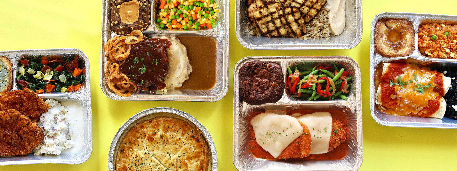 spread of tv dinners in tin containers on a yellow table
